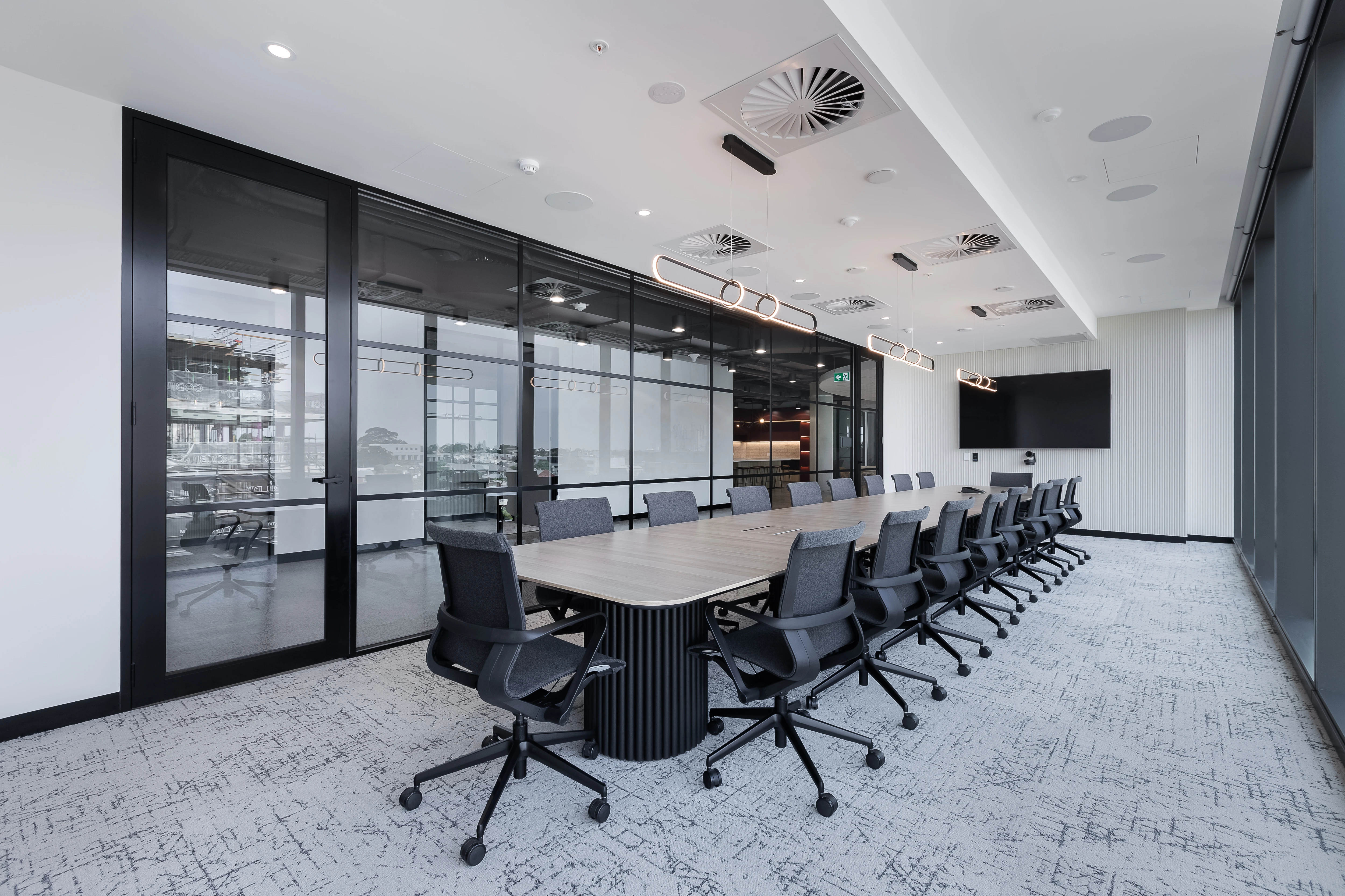 Coverforce boardroom with an expansive table on black fluted Steccawood Remi bases, Zed mesh meeting chairs and black-framed glass partitions
