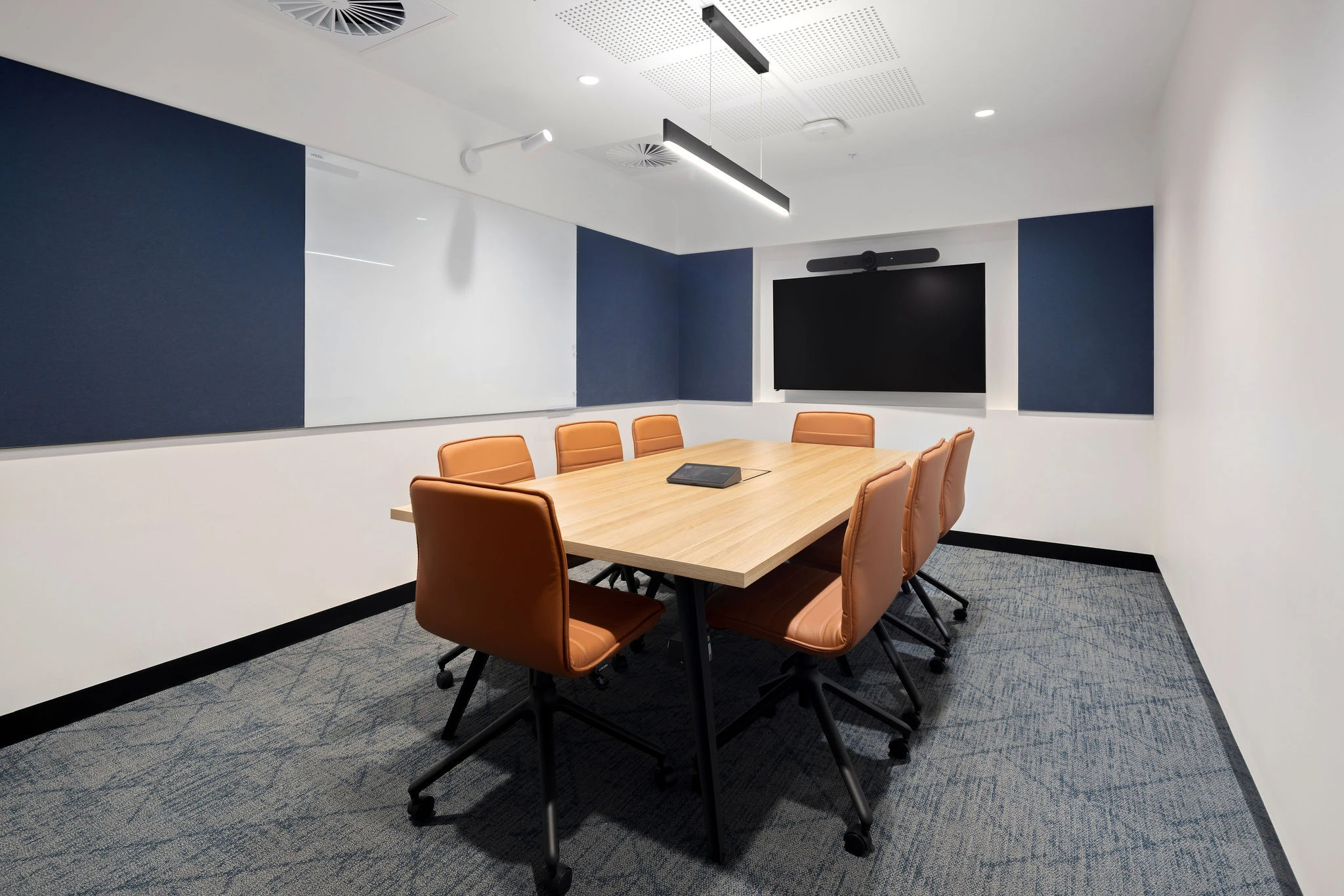 Compact meeting room with Alex task chairs in tan leather around a Dart table on tapered steel legs