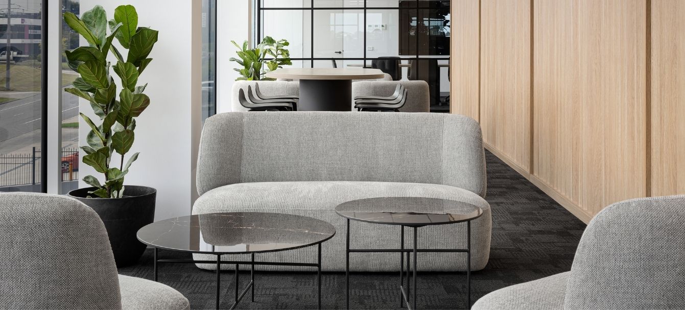 Reception lounge with a grey Franki lounge, Nest coffee tables and armchairs against timber wall panelling