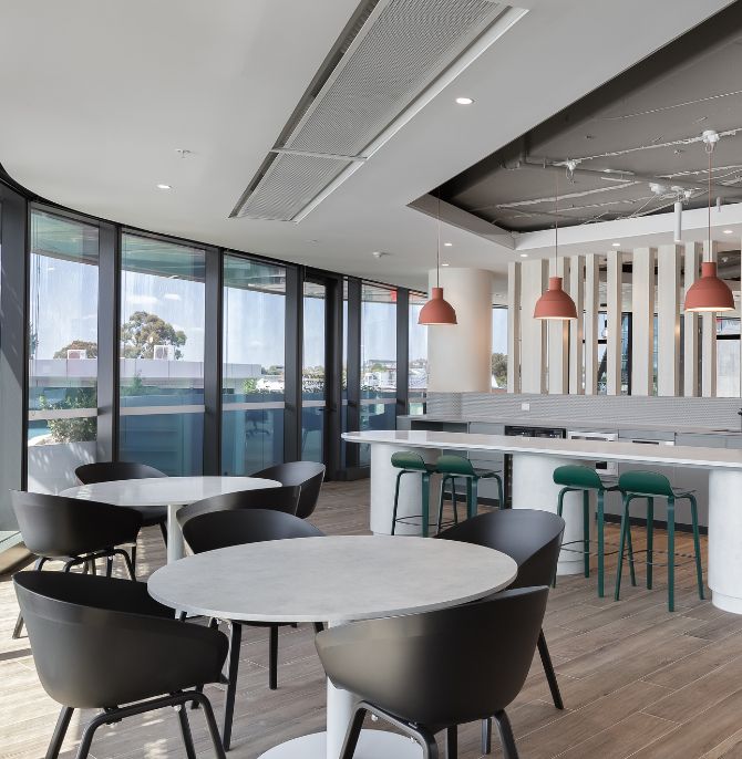 Kitchen dining area with round Cosmopolitan tables, black chairs and Indi stools at the bench