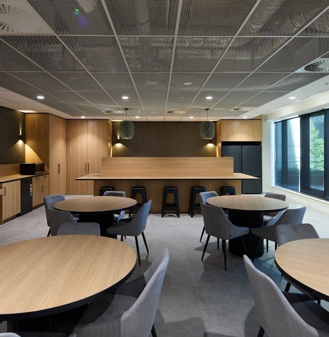 Breakout space with round timber tables, grey chairs and a counter-height table with stools