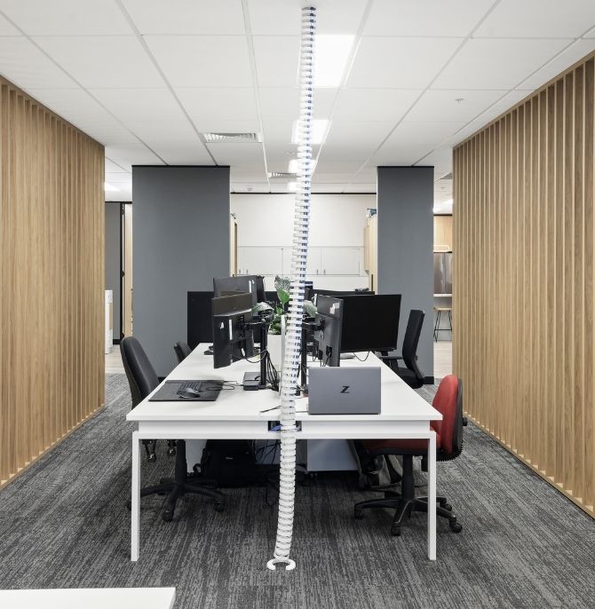 White workstation with dual monitors and task chairs framed by timber batten screens