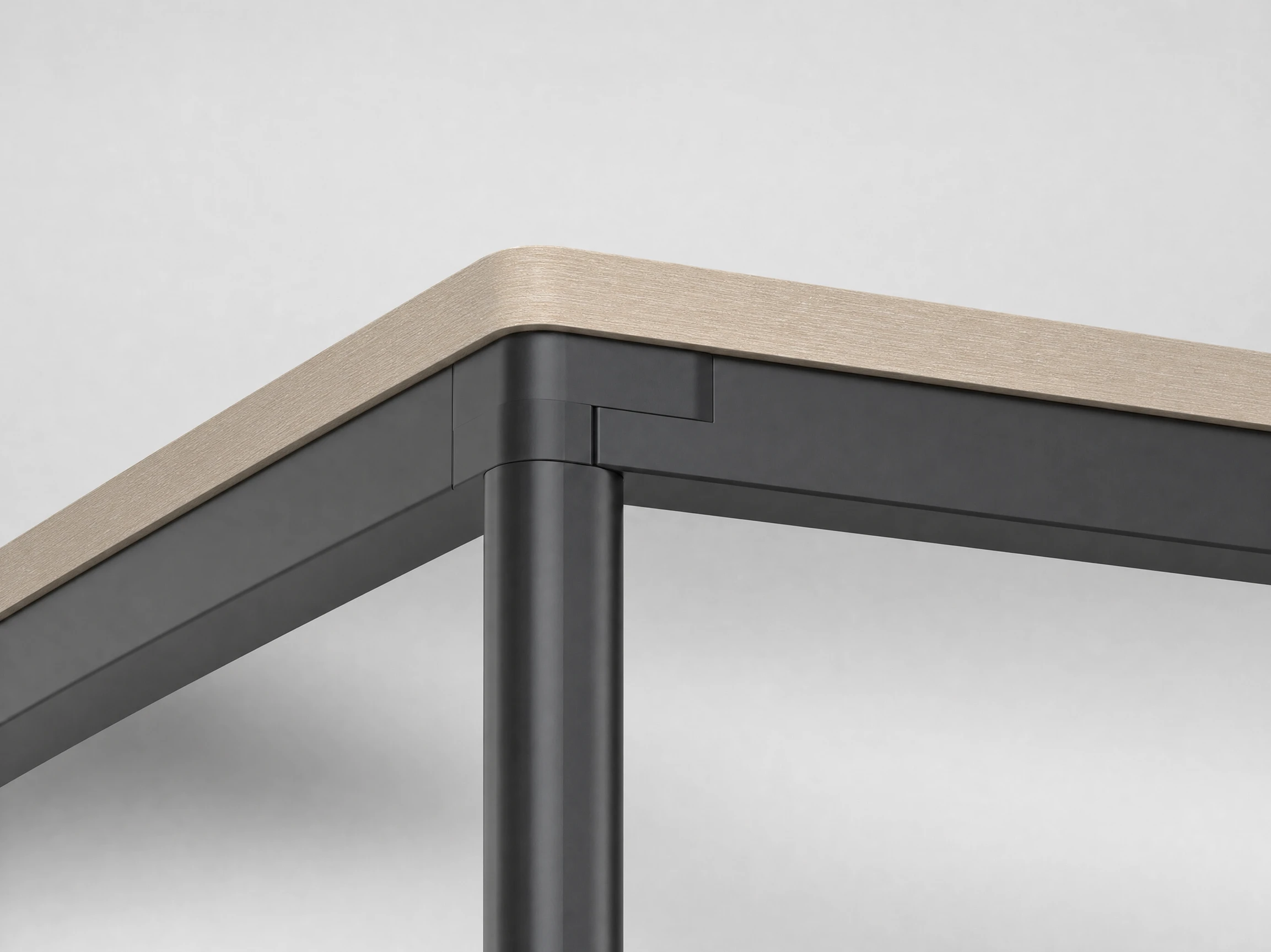 Close-up of the Clic multi-directional corner bracket joining leg and frame, angled workstation layout softly blurred behind