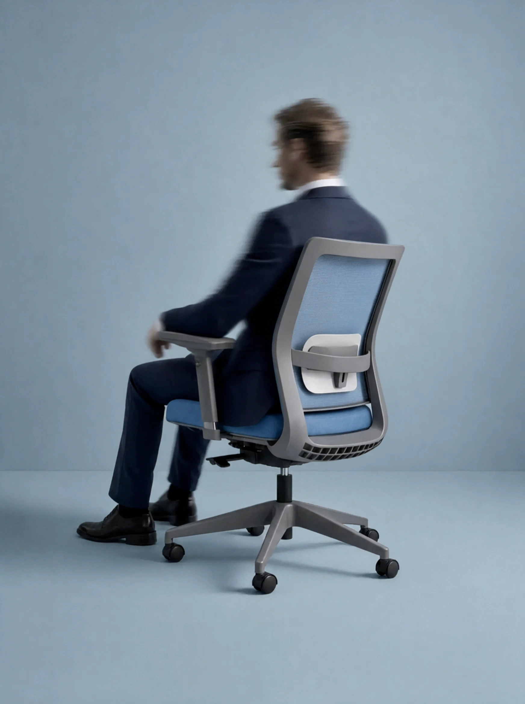 Hana in profile with a sitter leaning back naturally, relaxed posture, bright workplace background softly blurred